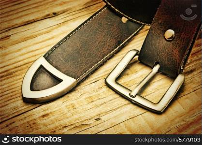 leather belt with a buckle on a wooden board. Toned