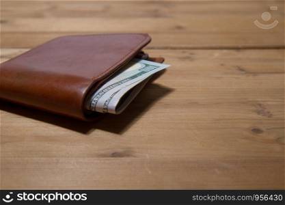 leather brown wallet with five hundred dollars on a wooden surface. wallet with dollars