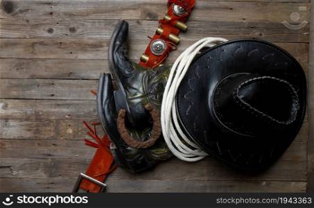 leather classic cowboy hat with lasso and horseshoe on rough wooden table