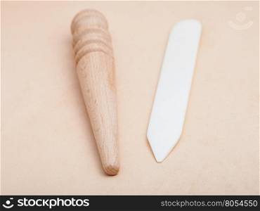 Leather crafting tool - flat plastic and round wooden slickers on natural leather