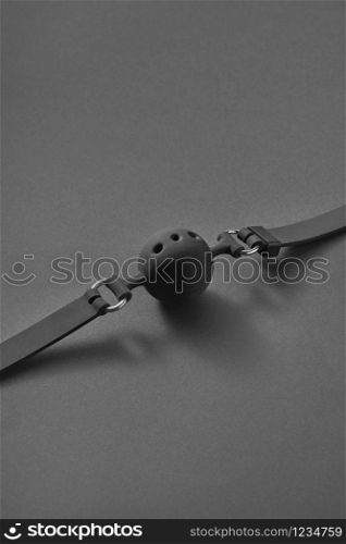 Leather sex attribute ball gag with small holes on a black background with shadows, copy space. Sex and erotic games concept.. Fetish attribute BDSM ball gag.
