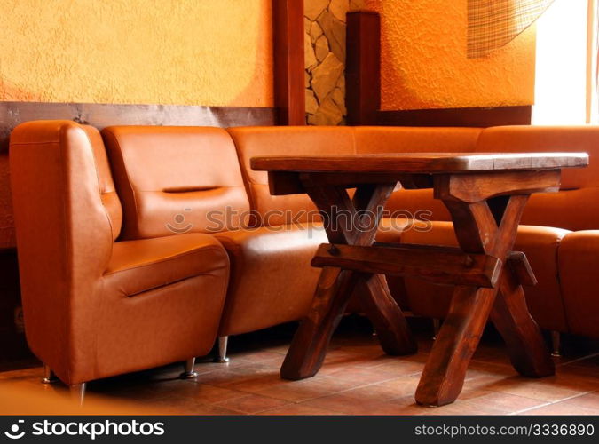 Leather sofa and wooden table in the corner of the hall near the window