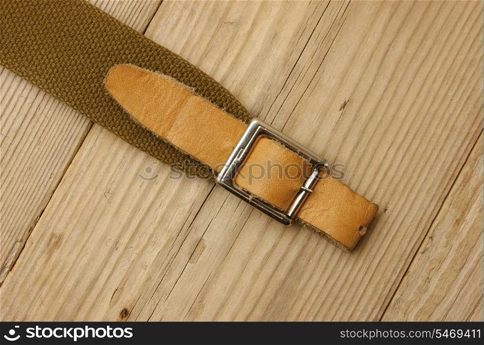 leather strap with a buckle on a wooden board