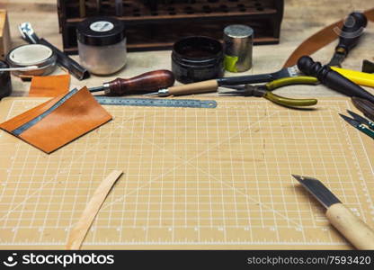 Leathermaker&rsquo;s work desk. Tools and leather at cobbler workplace. Tools for craft production of leather goods on wooden table.. Leathermaker&rsquo;s work desk