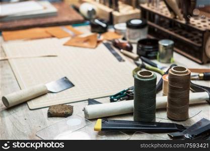 Leathermaker&rsquo;s work desk. Tools and leather at cobbler workplace. Tools for craft production of leather goods on wooden table.. Leathermaker&rsquo;s work desk