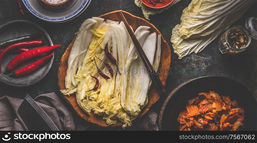 Leaves of chinese cabbage in wooden bowl for kimchi making with ingredients and chopsticks. Top view