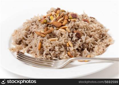 Lebanese spiced rice with minced beef and garnished with freshly toasted nuts on a plate with a fork