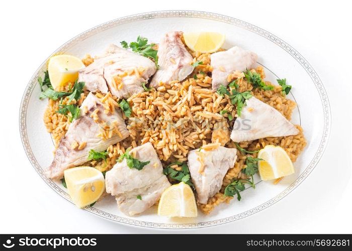 Lebaneses-style fried fish on a serving dish with caramelised onion-flavoured rice and roasted almond slivers, seen from above