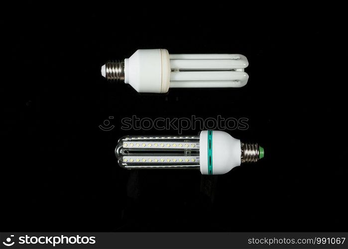 led and fluorescent energy saving lamps on black isolated background. on the glass
