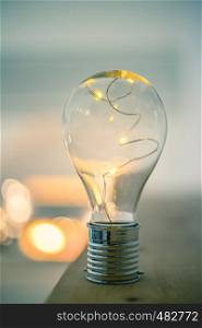 LED light bulb is lying on a wooden table. Symbol for ideas and innovation. Spot lights in the blurry background.