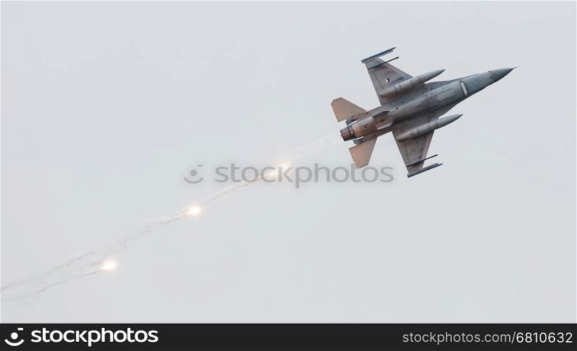 LEEUWARDEN, THE NETHERLANDS - JUN 11, 2016: Dutch F-16 fighter jet firing off flares during a flyby on it's European debut at the Royal Netherlands Air Force Days