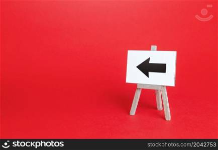 Left arrow easel sign. Direction pointer. Hint, help in navigation. Minimalism. Advertising and attracting attention. Redirecting traffic. Short road. Point at, show the way. Copy space