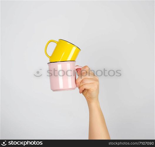 left female hand holding a stack of ceramic mugs, gray background, coffee time
