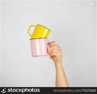left female hand holding a stack of ceramic mugs, gray background, coffee time