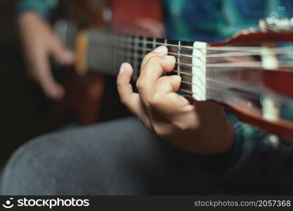 Left hand detail of a child with chord on classical guitar