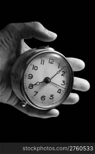 Left hand is holding an old alarm clock. Black background. Clipping path is included