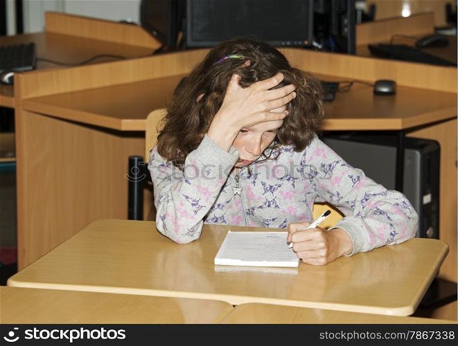 left handed girl writing on paper in school