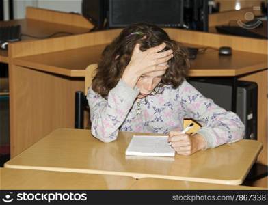 left handed girl writing on paper in school