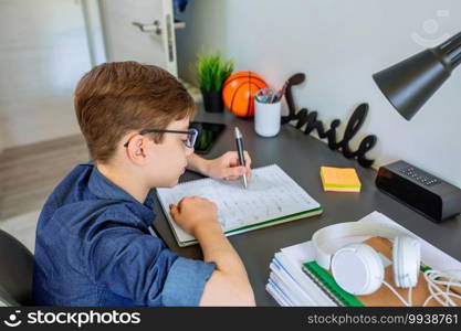 Left handed teenager doing homework on desk in his bedroom