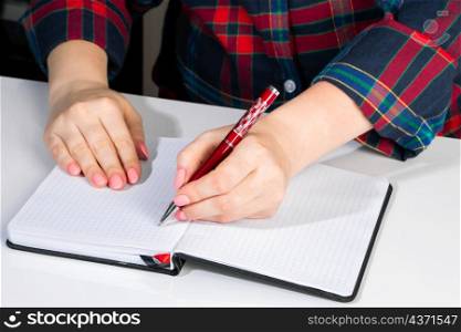Left-handers Day. Business woman writes a note in a notebook. Girl holds a pen in her left hand close-up.. Left-handers Day. Business woman writes a note in notebook. Girl holds a pen in her left hand close-up.