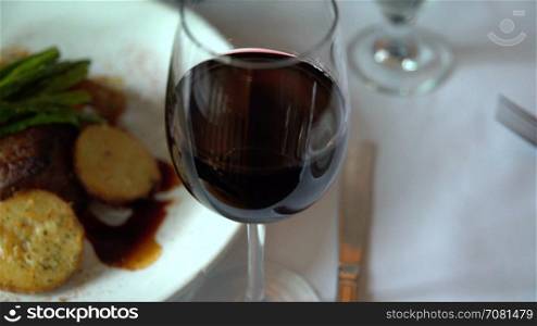Left pan of a fillet mignon meal with red wine