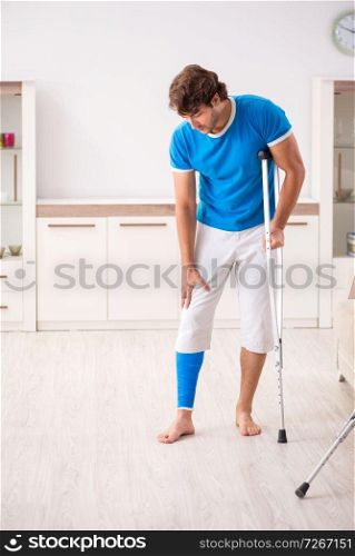 Leg injured young man with crutches at home 