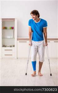 Leg injured young man with crutches at home