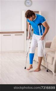 Leg injured young man with crutches at home 