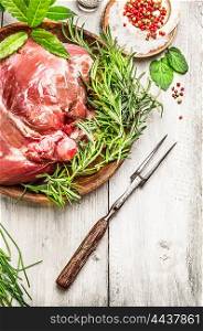 Leg of lamb with meat fork and fresh seasoning on rustic wooden background