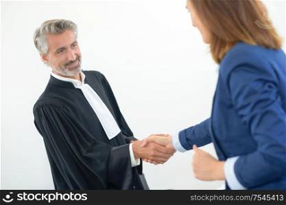 Legal worker in robes shaking hands with woman in suit
