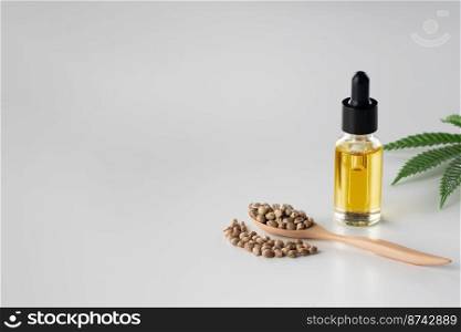 Legalized marijuana concept features with CBD oil extract from marihuana in glass bottle with dropper lid, piles of hemp seeds on empty background. Marijuana products for copyspace and advertising.. Legalized marijuana concept features with CBD oil for copyspace and advertising.
