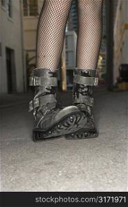 Legs and feet wearing boots of Caucasian young woman in urban setting.