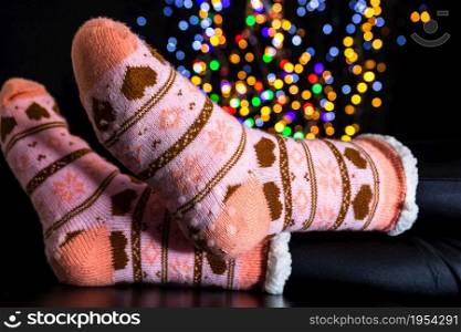 Legs in winter Christmas socks on blurred lights