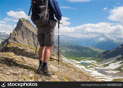 legs of a hiker wearing short and hiking shoes standing at the top of mountain with beautiful alpine landscape. egs of a hiker wearing short and hiking shoes standing at the top of mountain with beautiful alpine landscape