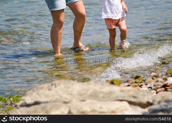 Legs of a mother and daughter . Legs of a mother and daughter in the water of the Garda Lake in Italy