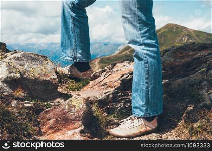 legs of a tourist man standing on the top of Alp mountains, valley beyond the mountain pass, beautiful landscape. Travel, adventure, freedom, challenge, hiking, vacation concept
