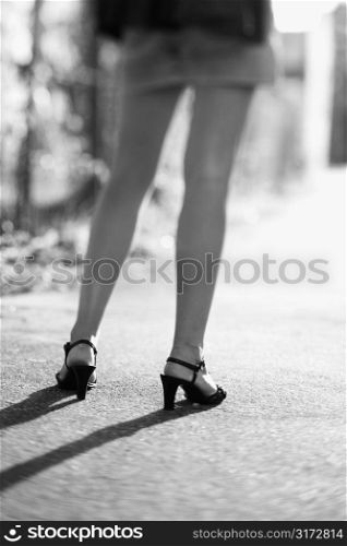 Legs of Caucasian mid-adult woman wearing blue jean skirt and heels.