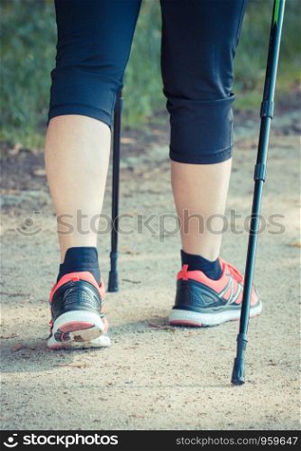 Legs of elderly senior woman in sporty shoes practicing nordic walking, healthy lifestyles in old age concept. Legs of elderly senior woman practicing nordic walking, sporty lifestyles in old age concept