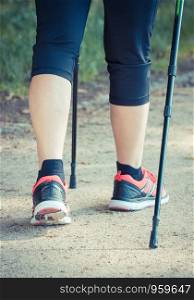 Legs of elderly senior woman in sporty shoes practicing nordic walking, healthy lifestyles in old age concept. Legs of elderly senior woman practicing nordic walking, sporty lifestyles in old age concept