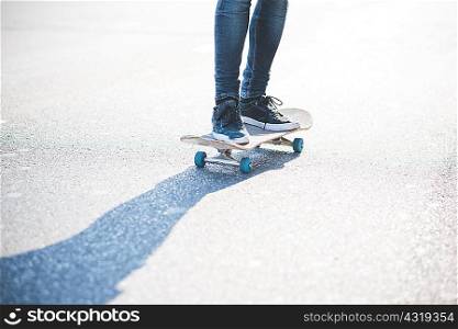 Legs of male urban skateboarder swerve skateboarding on road
