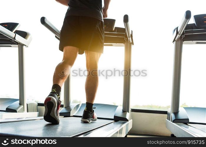 Legs of sportsman running on treadmill in fitness gym center. Sport and Healthy lifestyle concept. People workout and exercise activity. Back view or rear view