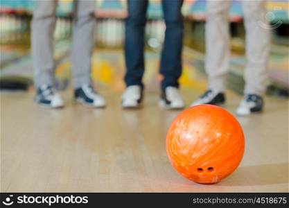 Legs of three men behind a bowling ball