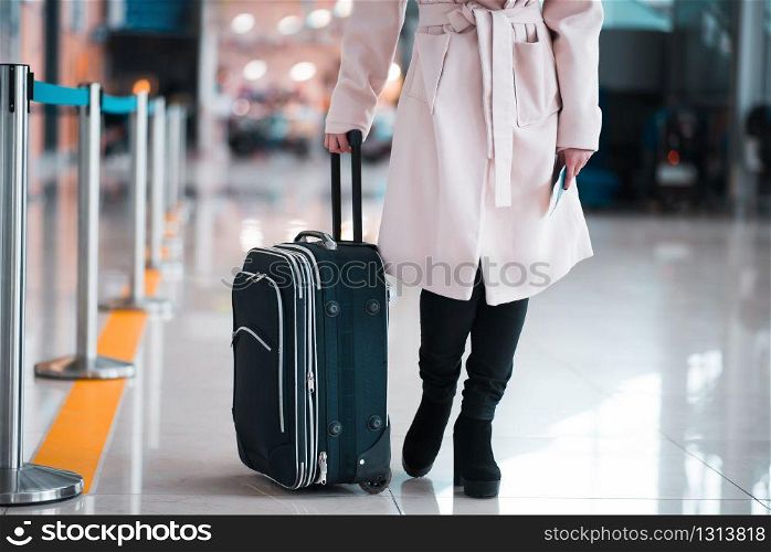 Legs of young businesswoman with baggage in airport. Travel concept.