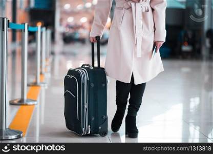 Legs of young businesswoman with baggage in airport. Travel concept.