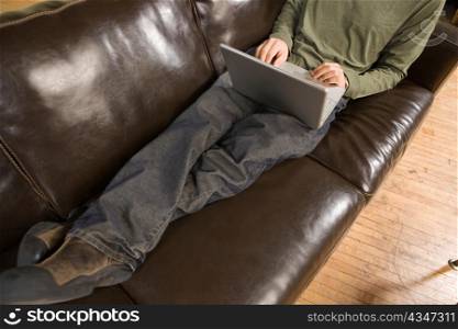 Legs of Young Man Computing on Couch