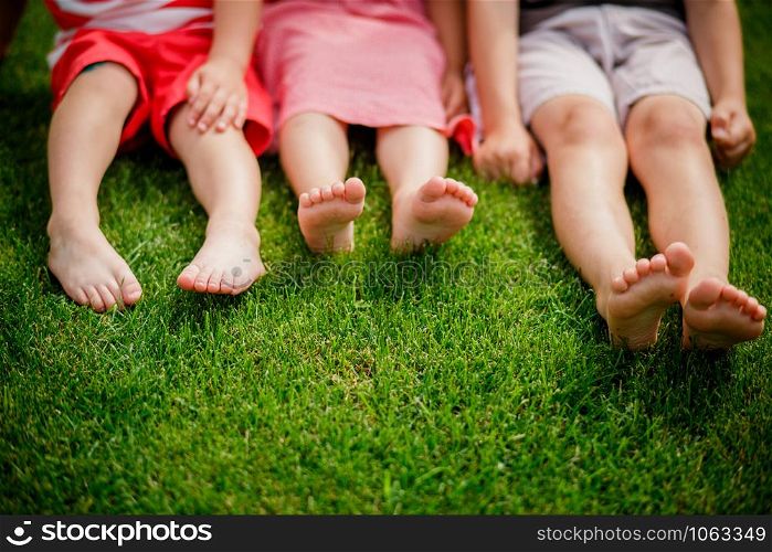 legs on the grass. bare legs of little girls sitting on the meadow. Selective focus, children sit on the grass with bare legs. children&rsquo;s legs on the grass. bare legs of little girls sitting on the meadow. Selective focus, children sit on the grass with bare legs