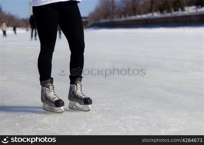Legs with ice skates on the ice during winter
