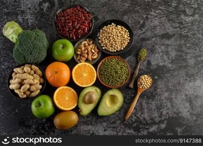 legumes and fruit on a black cement floor background.