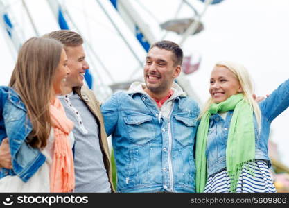 leisure, amusement park and friendship concept - group of smiling friends ferris wheel on the back