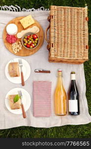 leisure and eating concept - close up of food, drinks and picnic basket on blanket on grass at summer park. food, drinks and picnic basket on blanket on grass